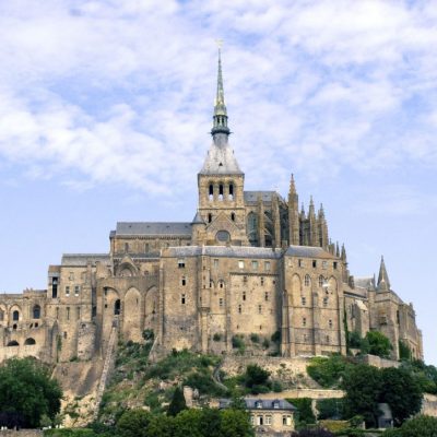 a castle with a clock tower in front of Mont Saint Michel Abbey
